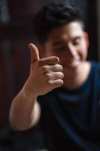A person is blurred out in the background with a crisp thumbs up in the foreground