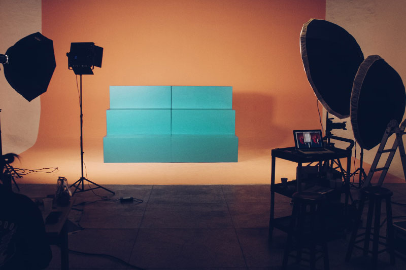 Studio setup with peach colored backdrop, teal stairs, and filming equipment